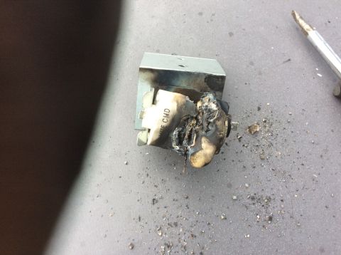 1992 Ford Bronco - A heavily damaged and burnt electrical component, possibly a transformer or relay, is shown on a gray surface. The component has melted pla…