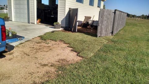 1995 Ford Bronco - The rear of a blue pickup truck is parked on a gravel driveway next to a garage. A section of sod has been removed from the lawn in front o…