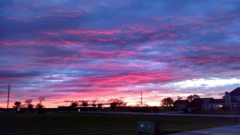 1995 Ford Bronco - A dramatic sunset paints the sky with vibrant pinks and purples over a suburban landscape with houses and trees silhouetted against the hor…