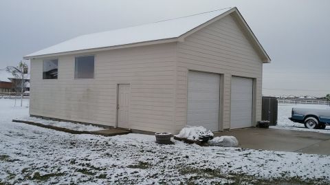 1995 Ford Bronco - A blue and white 1995 Ford Bronco is parked on a concrete driveway in front of a light-colored garage, partially covered in snow. The scene…