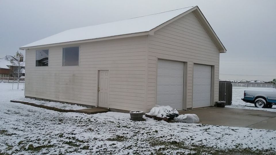 1995 Ford Bronco parked in front of a garage with snow on the ground.