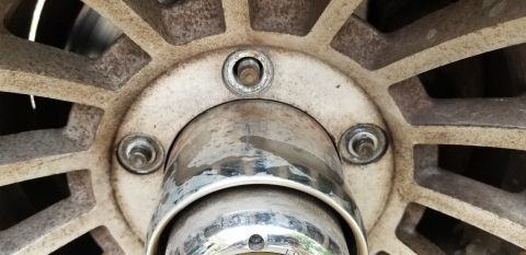 1995 Ford Bronco - A close-up view of a wheel hub and lug nuts on a vehicle, showing some wear and dirt. The wheel has a multi-spoke design and appears to be…