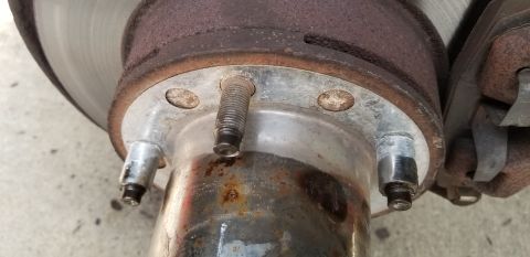 1995 Ford Bronco - A close-up view of a rusty vehicle hub with visible wheel studs and part of a brake rotor. The metal shows significant signs of wear and co…