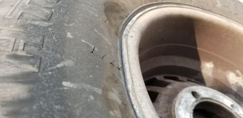 1995 Ford Bronco - A close-up view shows a flat tire on a 1995 Ford Bronco, with several small nails or staples embedded in the tread. The tire is mounted on…