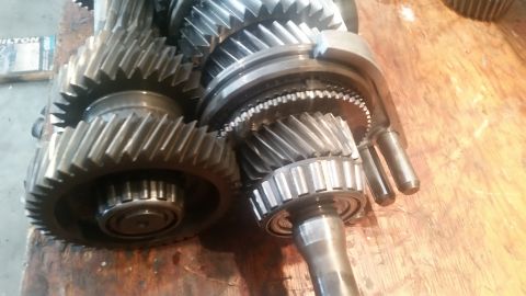 1985 Ford Bronco - A close-up view of several gears and a bearing assembly from a transmission, resting on a wooden surface. The gears are made of metal and s…