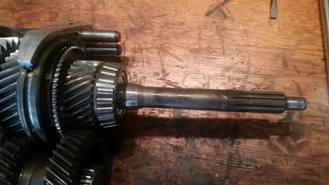 1985 Ford Bronco - A close-up view of a transmission input shaft with multiple gears and splines, resting on a wooden surface.