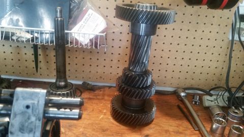 1985 Ford Bronco - A close-up view shows a transmission input shaft with several gears stacked on it, along with another shaft with a bearing. The parts are l…