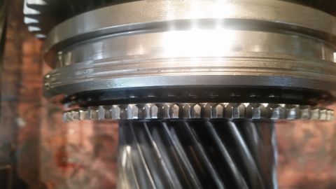1985 Ford Bronco - A close-up view shows the teeth of a metal gear assembly, likely part of a transmission or drivetrain. The gear is mounted on a splined sha…