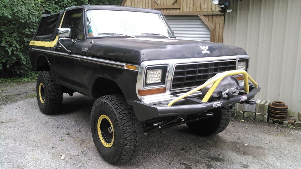 Lifted black 1978 Ford Bronco with yellow accents and custom bumper.