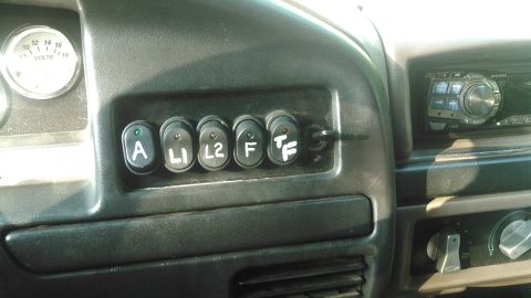 1992 Ford Bronco - A close-up view of a custom switch panel installed on the dashboard of a vehicle, featuring six toggle switches labeled A, L1, L2, F, and T…