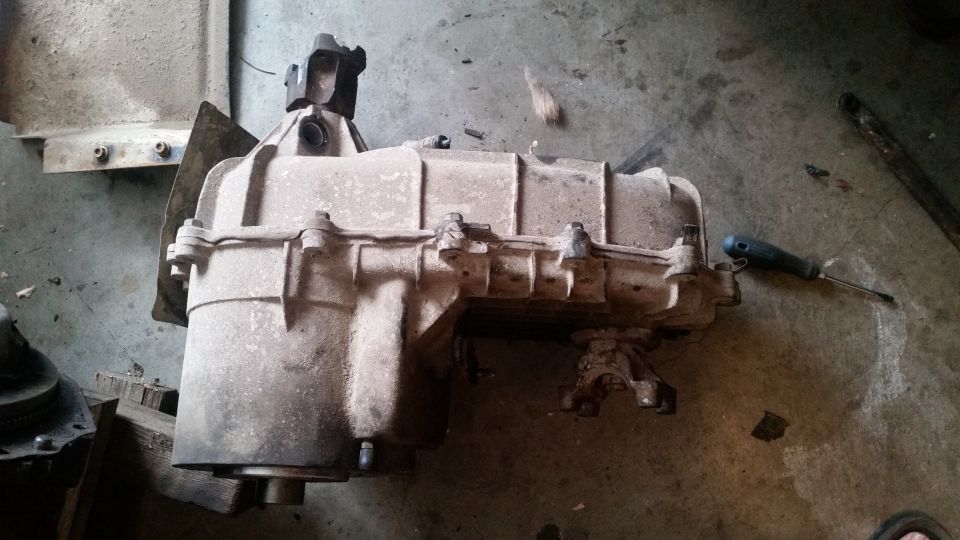 Dusty transfer case with a screwdriver on a concrete floor