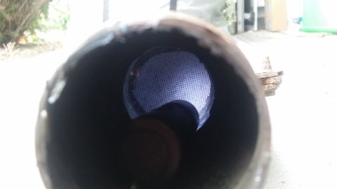 1985 Ford Bronco - View through the end of a metal pipe, showing a fine mesh screen inside. The pipe appears to be part of an exhaust system, with rough edges…