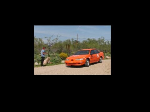 1993 Ford Taurus - Orange 1993 Ford Taurus with racing numbers seen at the finish line.