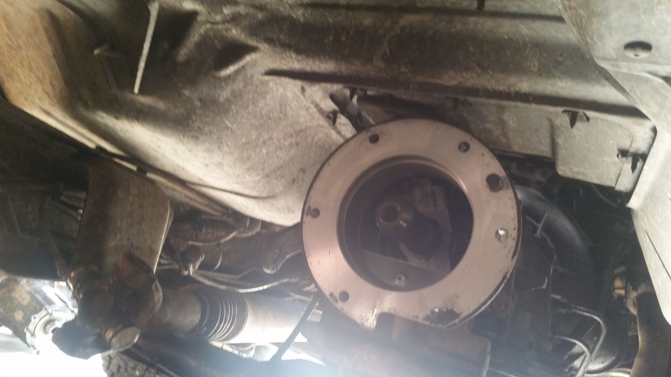 Underside of a vehicle showing transfer case adapter plate and driveshaft.