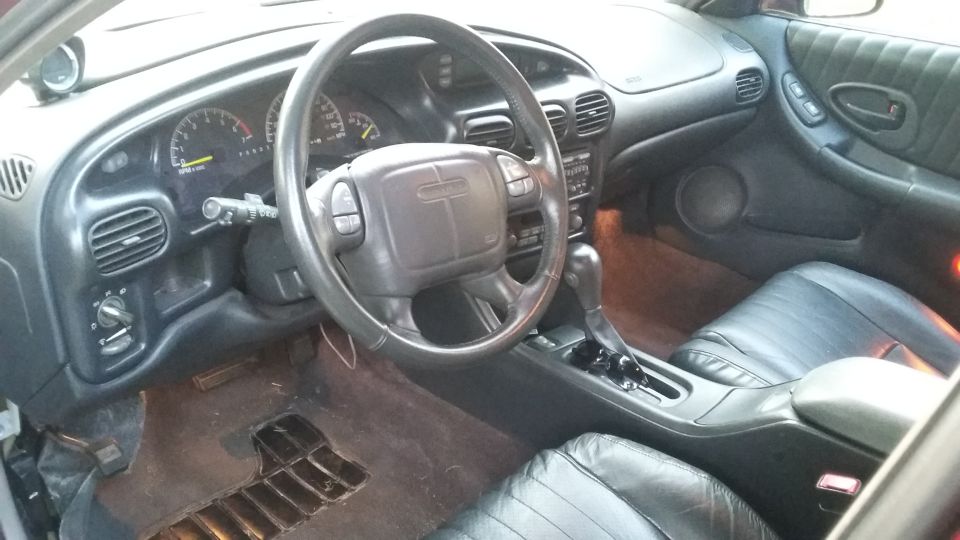 Interior of a 2000 Pontiac Grand Prix showing dashboard, steering wheel, shifter, and seats.