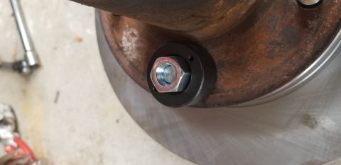 1995 Ford Bronco - A close-up view shows a lug nut with a specialized socket tool being used to tighten it onto a rusty brake rotor assembly. A portion of a s…