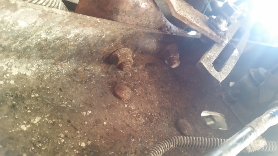 close-up of rusty metal frame and bolts, part of a vehicle's undercarriage