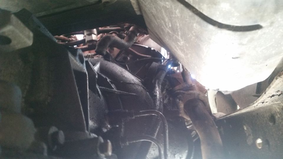 Underside view of vehicle drivetrain components, likely transmission and exhaust