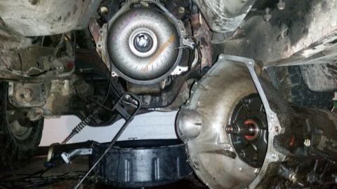1985 Ford Bronco - The vehicle's transmission and torque converter are disassembled, with a drain pan positioned below.