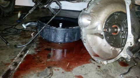 1985 Ford Bronco - Transmission fluid spill on garage floor with a transmission component nearby.
