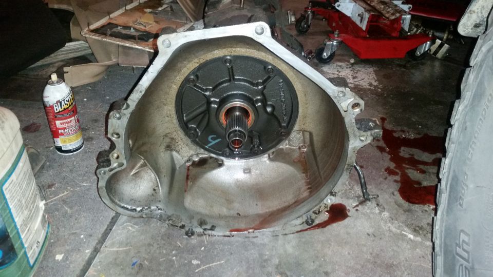Transmission bell housing with torque converter removed. Spray can and fluid on floor