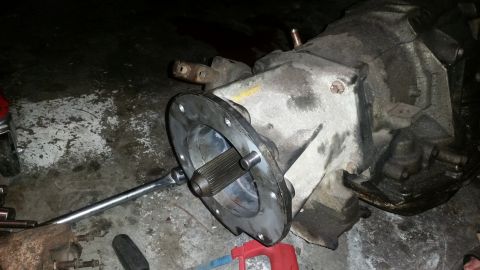 1985 Ford Bronco - A transmission part, possibly a transfer case, is shown with a splined shaft and bolt pattern on a workshop floor.