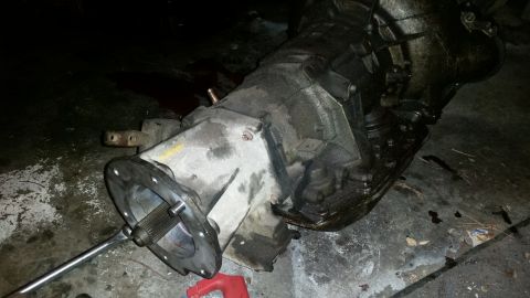 1985 Ford Bronco - Transmission and transfer case assembly on a concrete floor, possibly for a Ford Bronco.