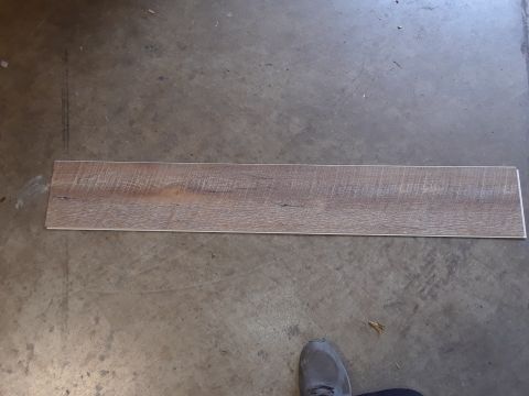 1999 Ford E250 - A single plank with a wood grain pattern lies on a concrete surface, with a shoe visible at the bottom right.