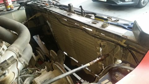 1985 Ford Bronco - Close-up view of a vehicle's engine bay, focusing on the radiator and associated hoses, with tools visible on the upper structure.