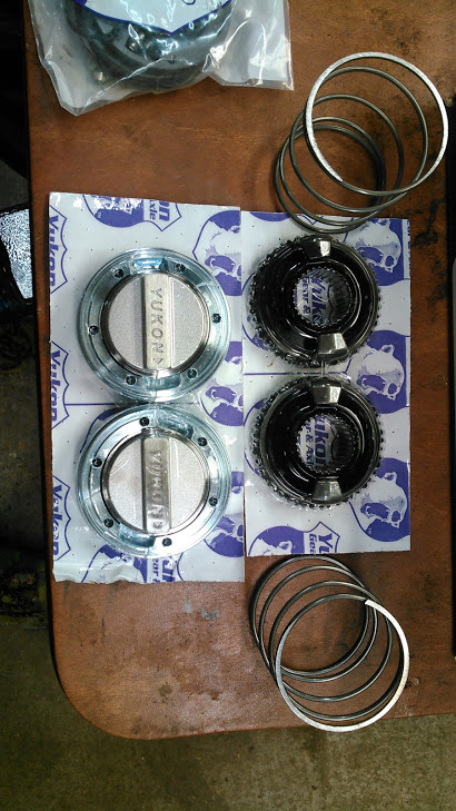1978 Ford Bronco - Yukon locking hubs and gears are laid out on a wooden surface, ready for installation.