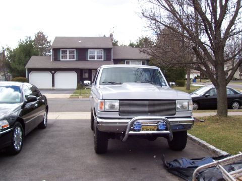 1990 Ford Bronco - Front view of a silver 1990 Ford Bronco with a custom grille and bull bar, parked in a driveway.