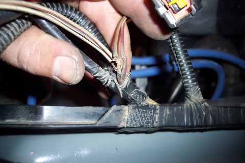 1995 Ford Bronco - Close-up view of a damaged wiring harness, showing frayed wires and electrical tape repairs.