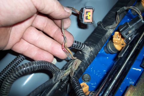 1995 Ford Bronco - Close-up of a damaged wire harness and fuel injectors, indicating a repair is needed.