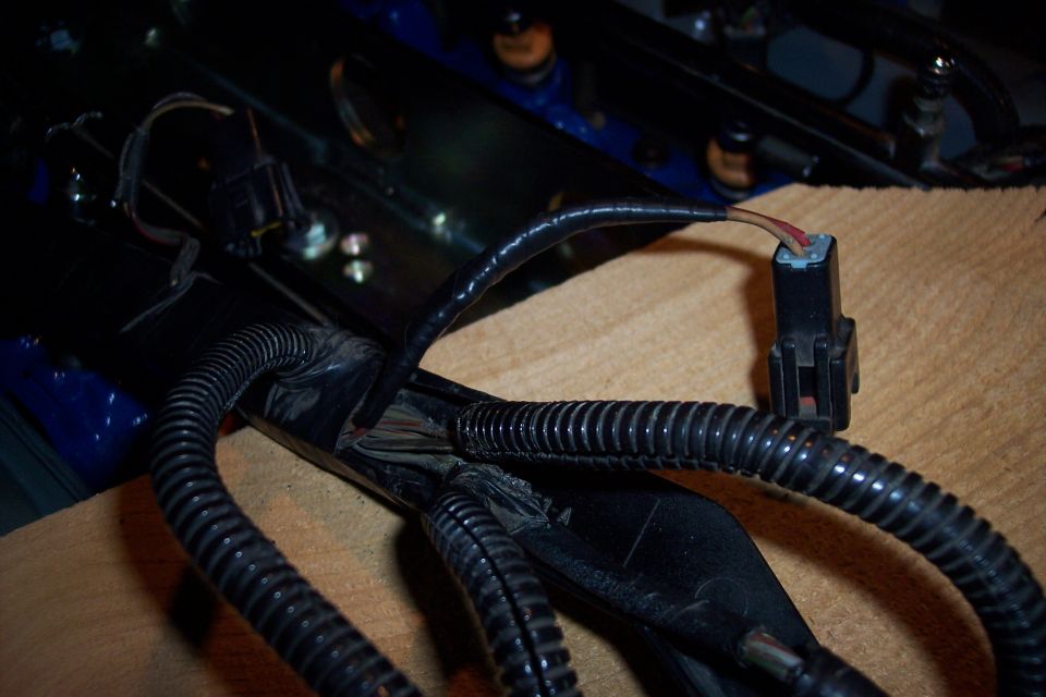 Close-up of a vehicle's wiring harness with black protective tubing and a disconnected electrical connector