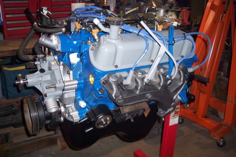 1995 Ford Bronco - Ford V8 engine assembly on an engine stand, showing the water pump, spark plug wires, and exhaust manifold.