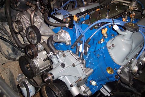 1995 Ford Bronco - Close-up view of a vehicle engine, showing various components and blue spark plug wires.