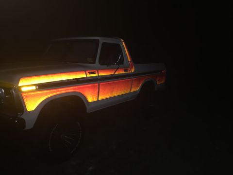 1979 Ford Bronco - A Ford F-Series pickup truck with distinctive side graphics is illuminated at night.