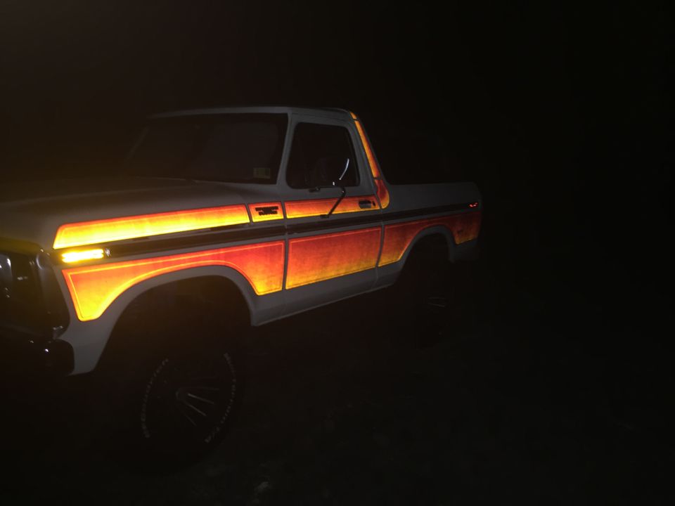 Ford F-Series pickup truck with orange and yellow stripe graphics on the side, seen at night