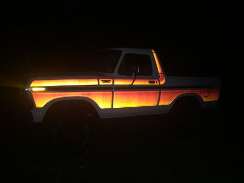 1979 Ford Bronco - A 1978 Ford Bronco with distinctive reflective side graphics is illuminated at night.