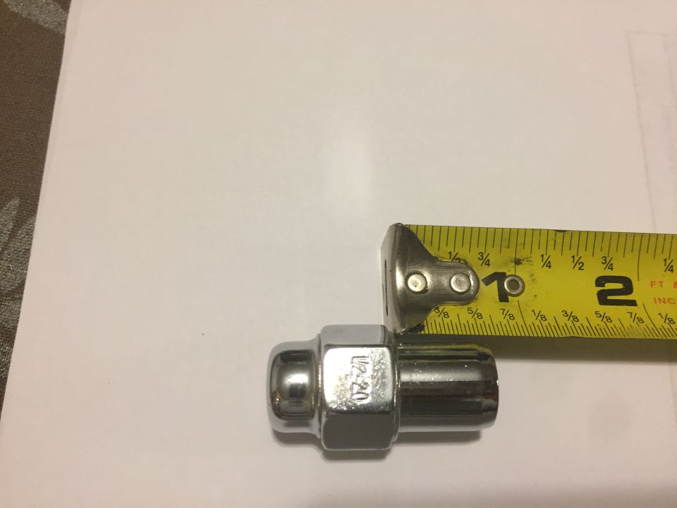 Chrome lug nut with 1/2-20 marking next to a tape measure showing 1 inch