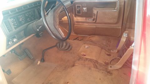 1985 Ford Bronco - Interior of an older truck, likely from the 1980s, with worn seats and floor.