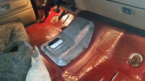 1985 Ford Bronco - The interior floor of a vehicle shows exposed carpeting and a removed console cover, suggesting modifications or repairs.