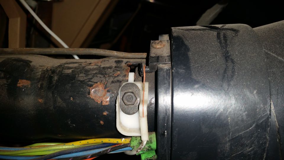 Close-up of rusty metal and wiring harness connected to a black plastic component