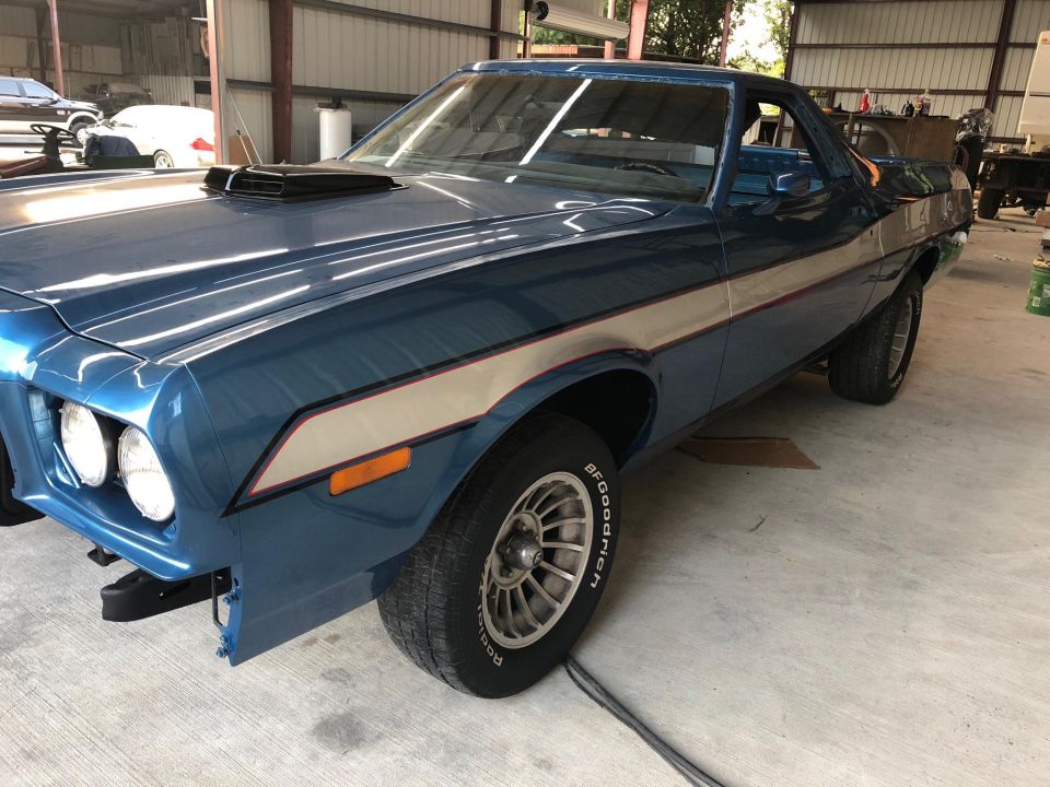 Blue 1973 Ford Ranchero with a scoop on the hood, seen from the front three-quarter view