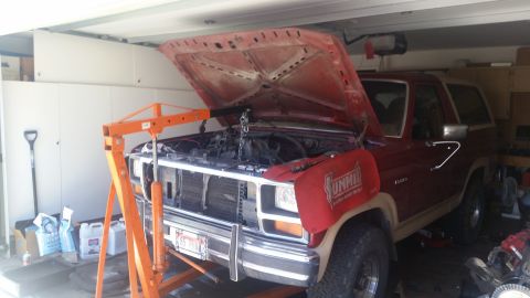 1985 Ford Bronco - 1985 Ford Bronco undergoing engine work with an engine hoist in the garage.