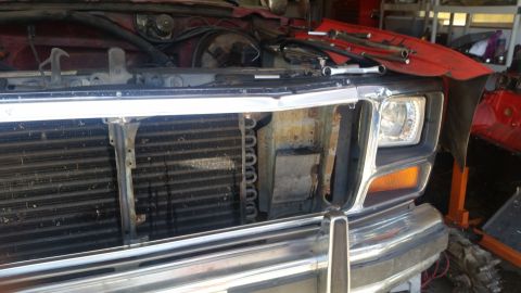 1985 Ford Bronco - Front view of a red Ford Bronco with its grille removed and tools laid out on the hood.
