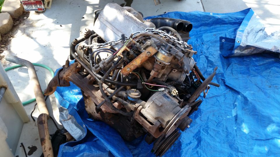 Engine assembly on a blue tarp, with exhaust pipe to the left