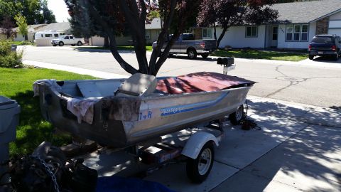 1985 Ford Bronco - An aluminum boat sits on a trailer in a residential driveway.