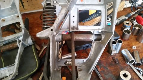 1985 Ford Bronco - A disassembled vehicle suspension component rests on a workbench alongside various tools.