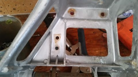 1985 Ford Bronco - Close-up of an aluminum bracket with visible mounting holes and signs of wear.